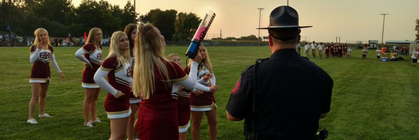 high school cheerleaders on football field with patrol officer standing nearby