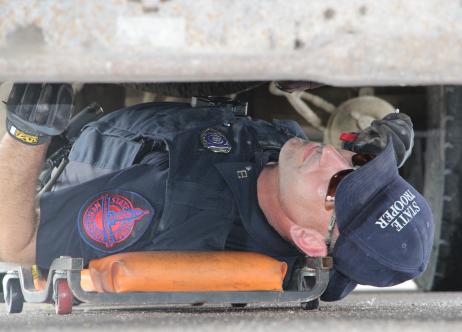 state patrol officer underneath vehicle performing maintenance