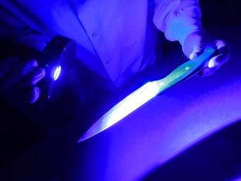 Examining a knife for fingerprints under a black light