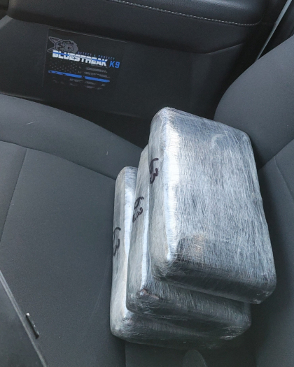 3 wrapped packages of cocaine sitting on the seat of a vehicle. 