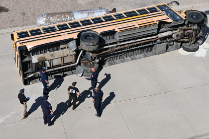 Several Carrier Enforcement Troopers inspect an overturned school bus. 